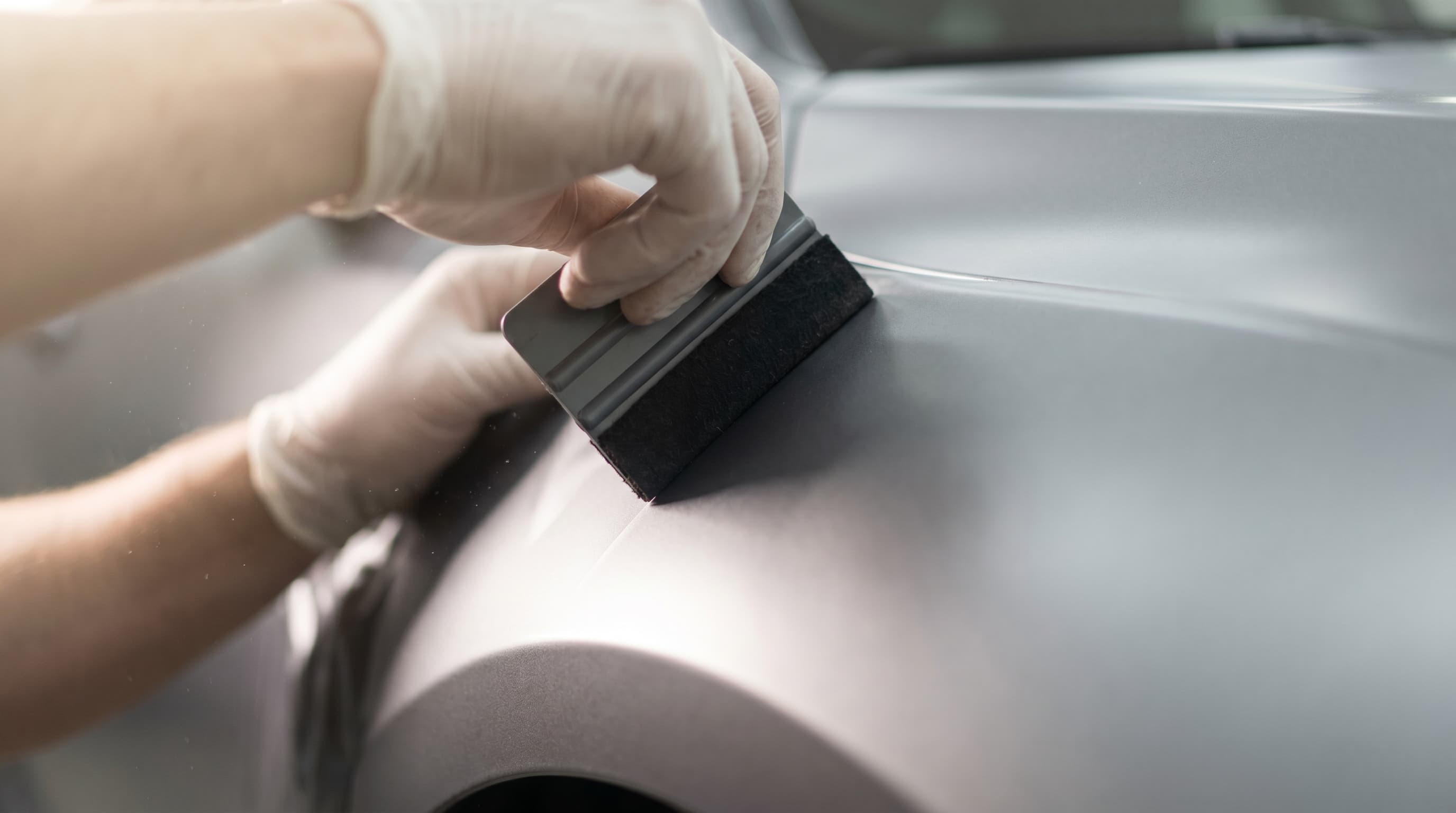 Installer's hands smoothing vinyl with a felt-edge squeegee